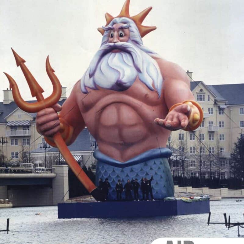 Massive hand-painted inflatable artwork of King Triton, created by Air Artists and commissioned by Disney for the grand opening of Euro Disney Paris in April 1992, floating on water with buildings in the background.